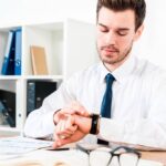 covek za radnim stolom gleda nasat na ruci